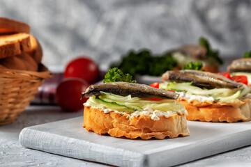 Smoked sprat sandwich - fish, fresh cucumber and tomato. Sprat sandwiches on toasted slices of bread