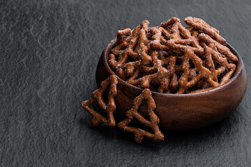 Christmas tree shapes pretzel in wooden bowl on stone background