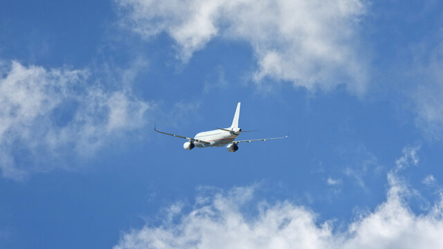 Zoom photo of passenger plane flying above deep blue cloudy sky