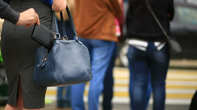 Woman on city street is unaware that her purse has been stolen by crafty pickpocket, She crosses the road through a pedestrian crossing. The thief stole her wallet from the bag