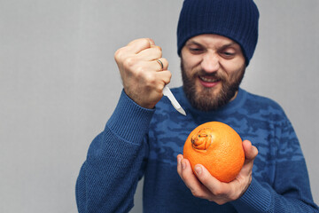 an angry bearded man wants to cut out the navel of an orange with a scalpel. concept of problems...