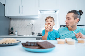 happy kid boy and father eating healthy peanut butter toast at home kitchen