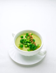 Green pea soup in a soup bowl on a white background