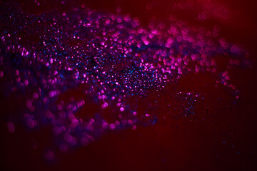 Purple glitter texture. Sequins are scattered on a black background. Shimmering effect. Bokeh.