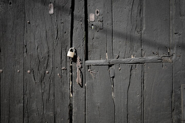 antique black wooden door with an handle and a padlock