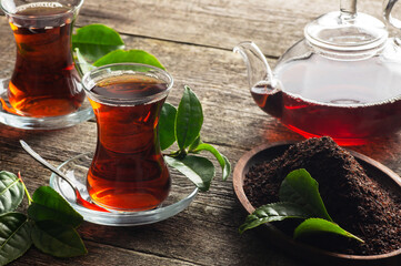 Glass cup of black tea with fresh and dry tea leaves, traditional turkish brewed hot drink