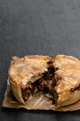 Puff pastry steak pie on baking paper on stone background