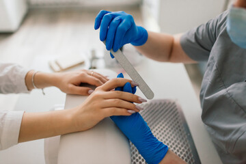 Female manicure master in a beauty salon work with hands of the client