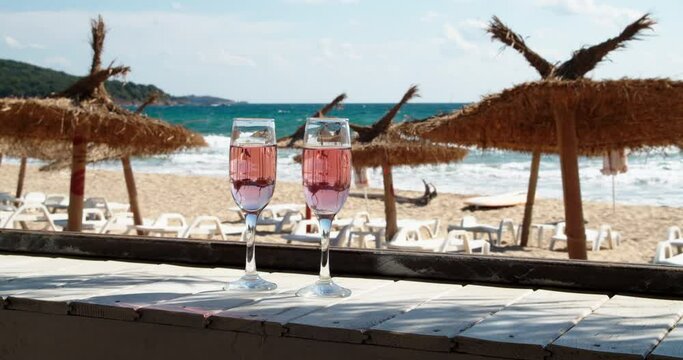 Two glasses with rose wine on the beach bar on a hot summer day, 4k slow motion