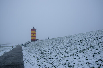 Otto lighthouse in Pilsum in the snow with fog in winter