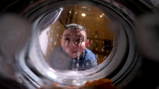 A child looks in surprise into a working washing machine