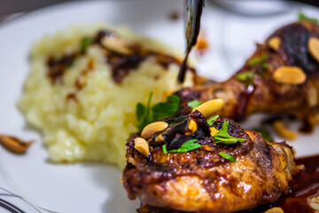 Thai chicken decorated with fresh parsley and peanuts on plate with blured rice