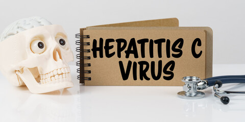 On the table lies a skull, a stethoscope and a notebook with the inscription - HEPATITIS C VIRUS