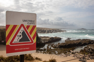 Coastline with warning cliff sign, Porto Covo, Sines, Portugal.