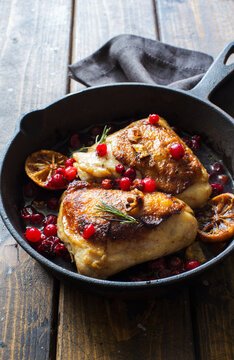 Fried Chicken Thighs With Lemon And Cranberries In A Skillet On Wooden Table