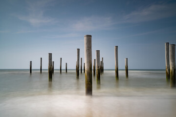 Focus on fLong exposure seascape. Taken at the North Sea in Petten with the pole village in the sea, Blue sky, sun and shodows. Focus on foreground