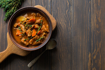 Bowl of beef stew on dark wooden table