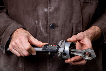 A mechanic measuring the piston of an internal combustion engine. Work in a mechanical workshop.