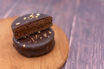 A chocolate alfajor filled with dulce de leche, on a wooden board