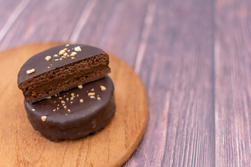 A chocolate alfajor filled with dulce de leche, on a wooden board