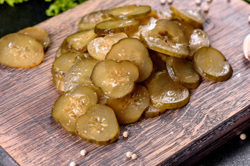 Tasty salty spicy pickled cucumber cut with rings on a wooden cutting board