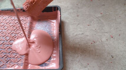 Man poring out paint into a tray. The guy pours red paint into the tub.