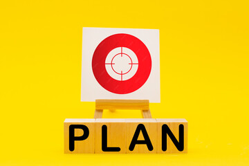 The word PLAN and sign stand on a yellow background. Hit exactly on center. Tactics of advertising targeting. advertise campaigns. Goal Achievement and Purposefulness