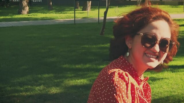 Nice young lady smiling and touching her face in summer park. Slow motion shot.