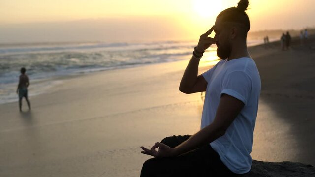 Mental harmony and meditation training during evening yoga at seashore beach, Caucasian male in lotus pose thinking and breathing keep praying while practicing concentration in asana 