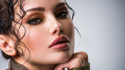 Closeup portrait of a beautiful young fashion woman with brown makeup posing at studio.