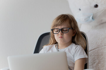 Angry girl of 5 years old is working at laptop