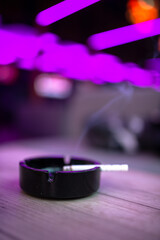 Vertical shot of a cigarette in an ashtray on a wooden table