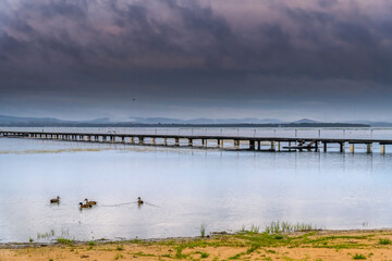 Rainy day sunrise waterscape with wharf