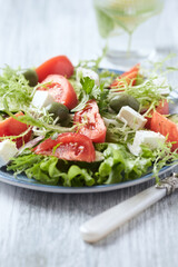 Salad with Green Olives, Tomatoes and Feta Cheese. Bright wooden background. 