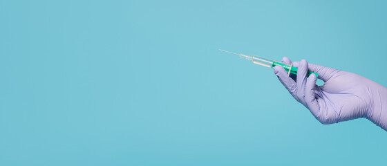 Syringe for injection in hand, latex medical gloves on hand. On a blue background, banner.