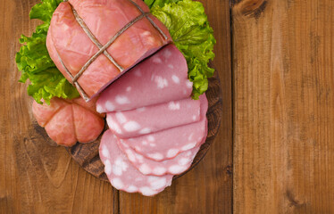 Italian Whole block of mortadella on a wooden plate decorated with green salad. Traditional big...