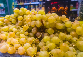 green grapes are sold on a shelf in the market in the fruit and vegetable section