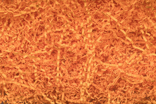 Orange confetti shredded crinkle paper for gifts and stuffing in cardboard boxes. Flat lay.