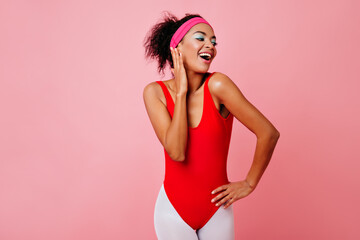 Emotional black young woman posing on pink background. Adorable sporty girl laughing and looking around.