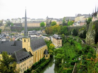 Fototapeta na wymiar View of Luxembourg City with Alzette River passing through the Grund Quarter and Abbey de Neumunster. Typical houses with black slate roofs in Luxembourg City
