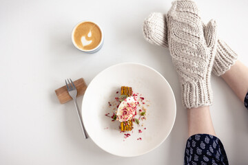 Women's mittened hands hold a coffee mug