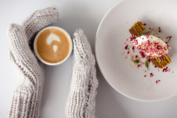Female hands in mittens with coffee and cake