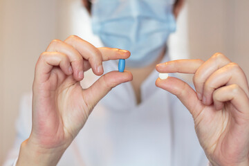 Doctor with surgical mask holding medical pills. Codiv-19 pill treatment concept