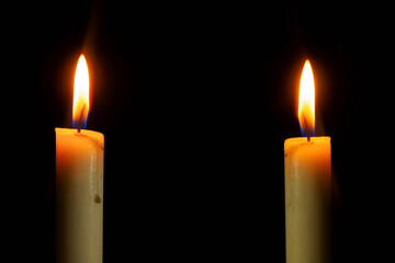 Two Candle light burning brightly in the black background, blank and wide background for copy space.