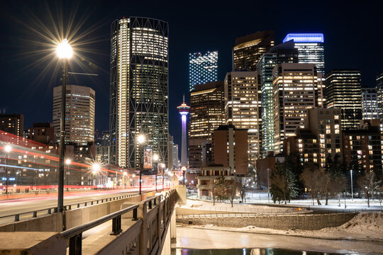 A long exposure night photograph of downtown Calgary Alberta Canada with light trails from vehicles across a bridge.