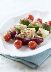 Grilled shashliks with vegetables and chicken. Bright wooden background. Close up. 