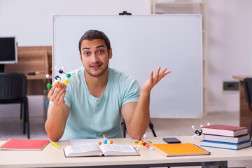 Young male student physicist studying molecular model at home