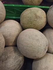 a few piles of melons in a supermarket