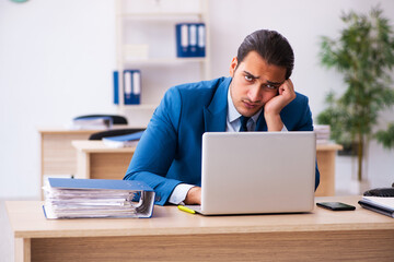 Young businessman employee unhappy with excessive work in the of