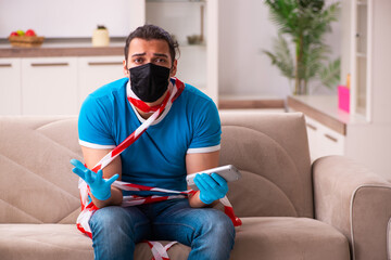 Young man watching tv at home in pandemic concept